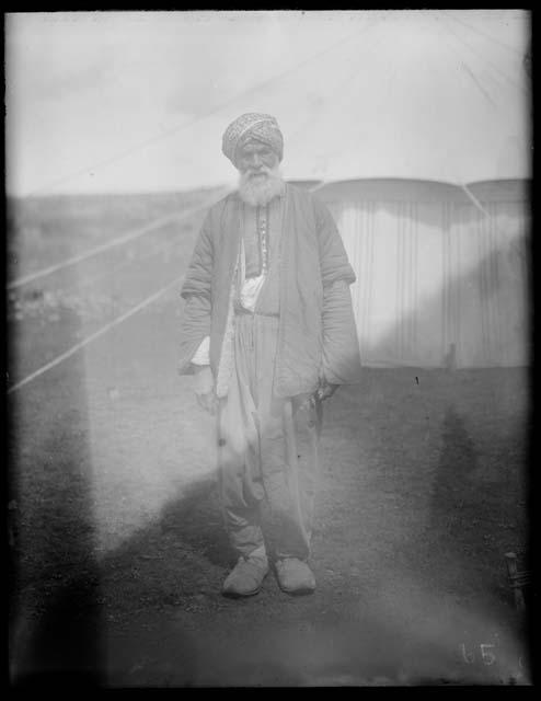 Man in traditional clothing in front of tent