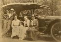 Family around car, man, three women, and a child