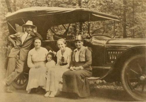 Family around car, man, three women, and a child