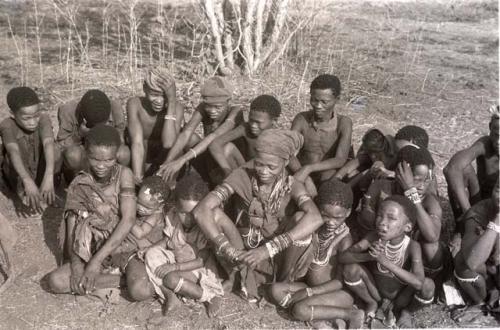 Tsamgao, /Gunda, "≠Gao Lame" (headman of Band 1), unidentified man, ≠Gao (son of Gau), Gau (husband of Be and Khuan//a), and !Naishi (with headband) sitting in the back row; and ≠Nisa (wife of //Ao) with her baby, unidentified girl, unidentified woman (possibly from / /Ti!kay's group), unidentified child, "Little ≠Gao" (son of /Qui and //Kushay) and //Kushay (behind "Little ≠Gao") sitting in the front