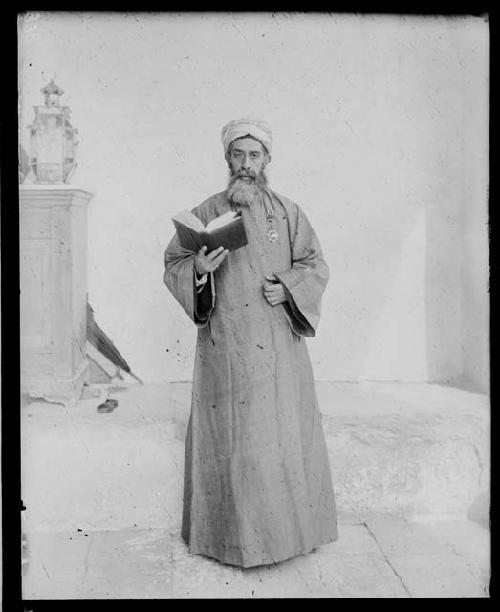 Man in traditional dress holding a book