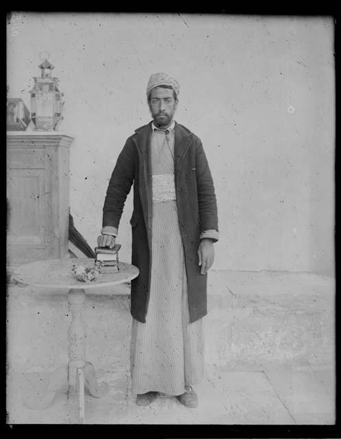 Man in traditional dress with hand on books