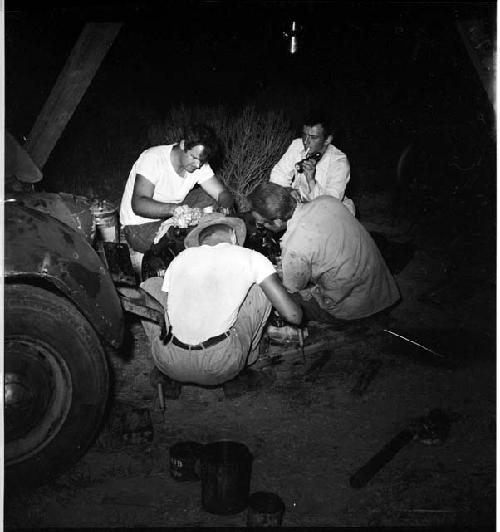 Four men work at night next to a truck