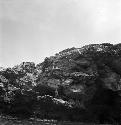 Man stands on rock formation/island (picture taken from water)