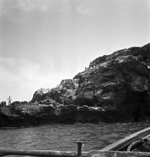 Several people on rock formation/island (picture taken from water)