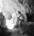 Two people sit at excavation site