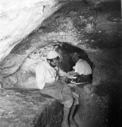 Two men sit at excavation site