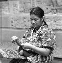 Woman weaves as she kneels on floor of Peabody Museum