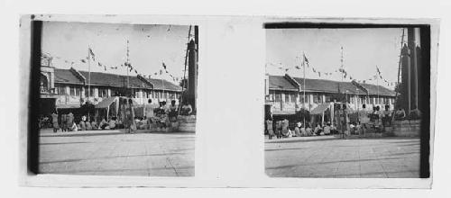 stereo glass slides; plaza scene, people seated, prayer flags, tent