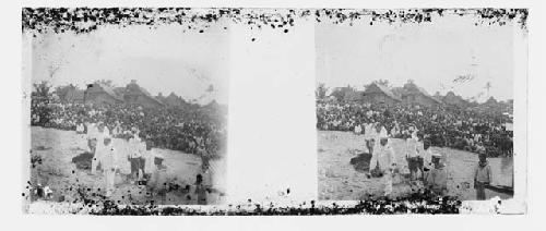 stereo glass slides; crowd of men, huts in background