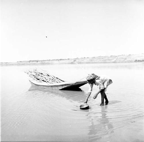 Woman works next to boat on Indus river at Pattan Ferry