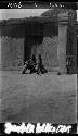 Man and children outside doorway of house