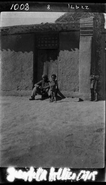 Man and children outside doorway of house