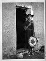 Hopi woman standing in a doorway and holding a basket