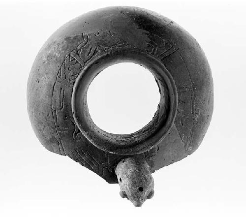 Round artifact with hole in the middle, carvings and head