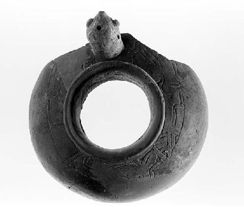 Round artifact with hole in the middle, carvings and head