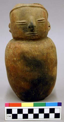 Ceramic effigy jar, human form, brown, undecorated, slit eyes and mouth, perfora
