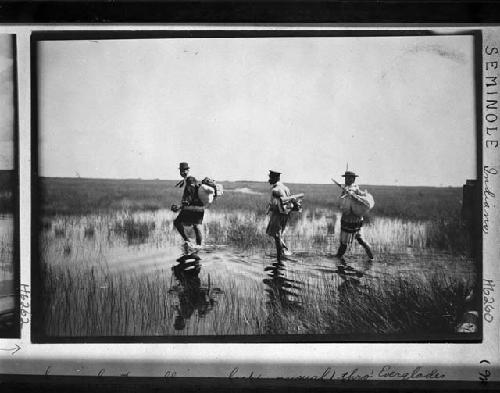 3 Seminoles traveling on foot throught the Everglades