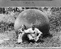 Samuel K. Lothrop and his wife Eleanor seated before a large stone ball. 1949