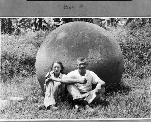 Samuel K. Lothrop and his wife Eleanor seated before a large stone ball. 1949