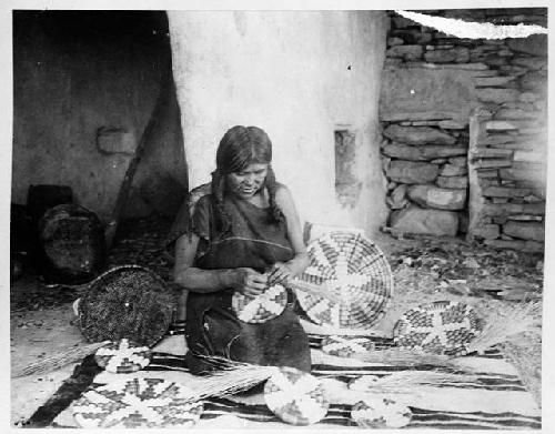 Hopi woman weaving coiled basket plaques with geometric designs typical of early Hopi basketry