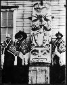 Haida standing next to totem pole