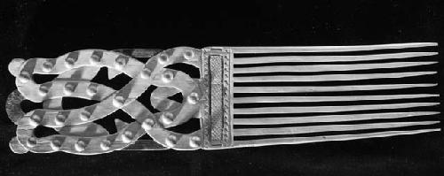 Carved wooden comb with metal knobs as part of the decoration