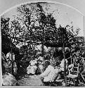 Men and women seated under arbor