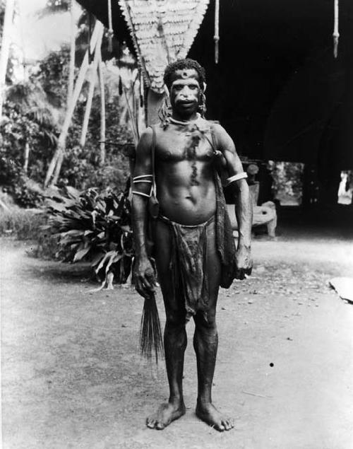 Native with lime gourd under arm