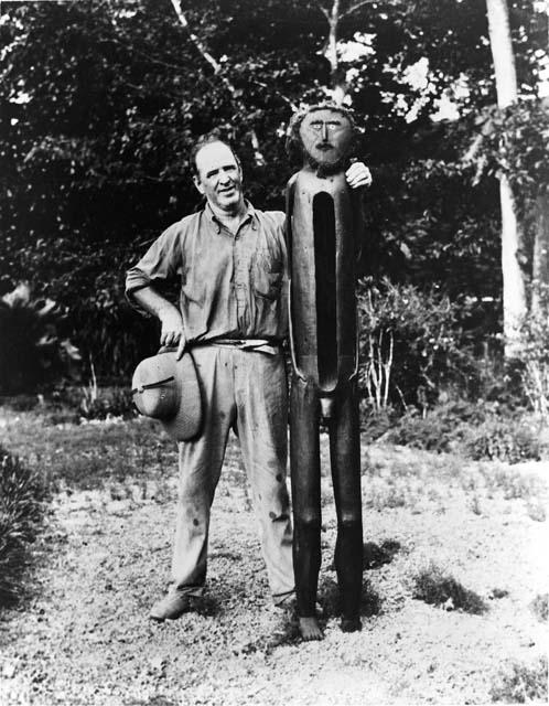 Man standing next to carved figure