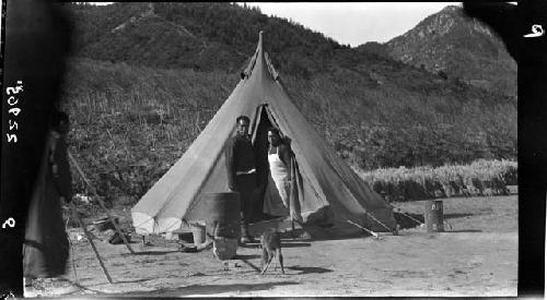 Two people stand outside tent