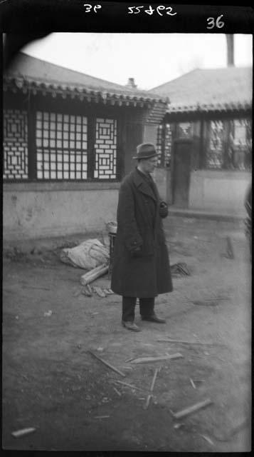 Man in overcoat standing in courtyard