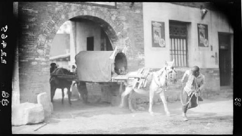 Man leads horse and wagon through gate