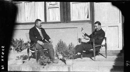 Two men seated, talking