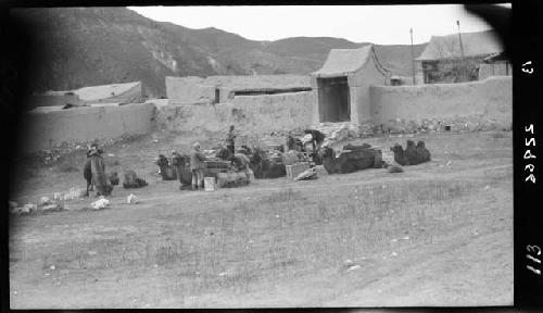 People load pack animals in a field