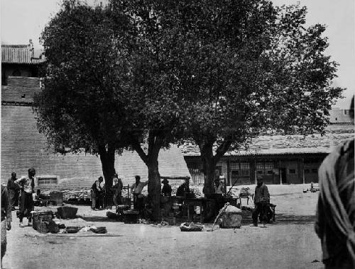 Merchants selling their goods under the trees of 'market square'