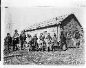 Group of Liard River Indians in front of log cabin