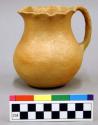 Ceramic pitcher, one handle, scalloped rim, orange micaceous slip.