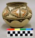 Pottery vessel with black and red design on white background