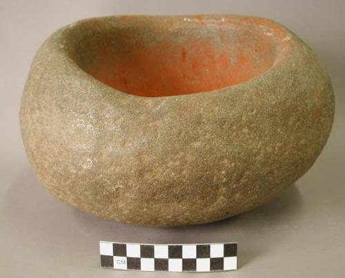 Ground stone mortar with remains of red pigment inside