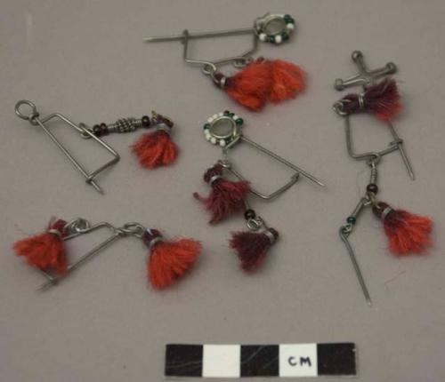 Metal ornamental saftey pins decorated with beads and red fiber