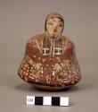 Female human effigy bottle, snakes painted on front, spout broken