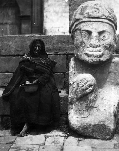 Old woman beside a large stone statue