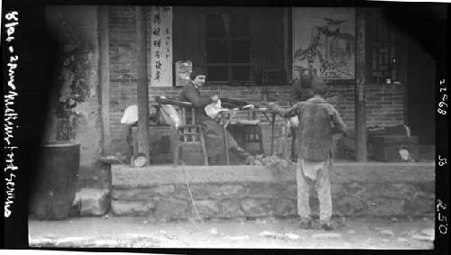 Woman seated outside, talking to two men