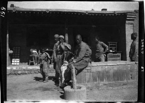 Men and children seated outside building