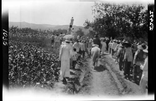 People walking down road in single-file lines