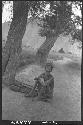 Man seated on ground below tree