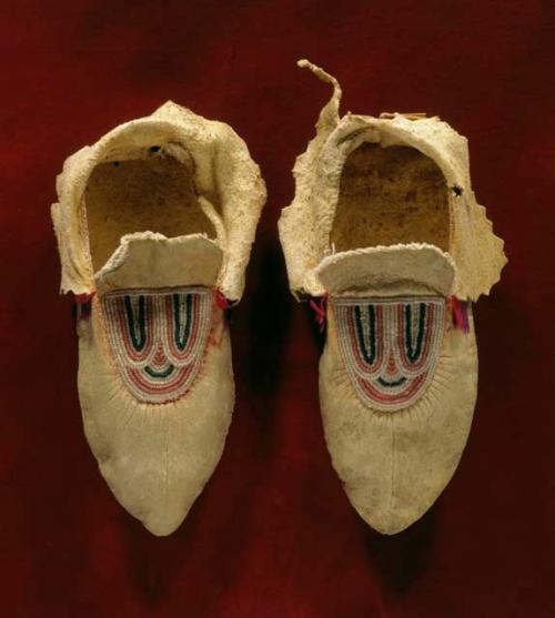 One pair of skin moccasins with bead decoration - pink, purple ribbon also used