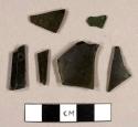 Olive green bottle glass fragments, one piece burned, one piece flat