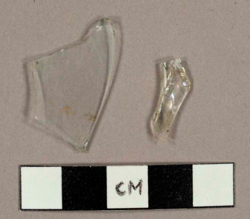 Colorless curved glass fragments, including one fragment possibly from a hurricane lamp, one base fragment from stemware vessel, and one base fragment from small bottle